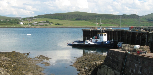 a trawler and small boat against the harbour wall at aultbea